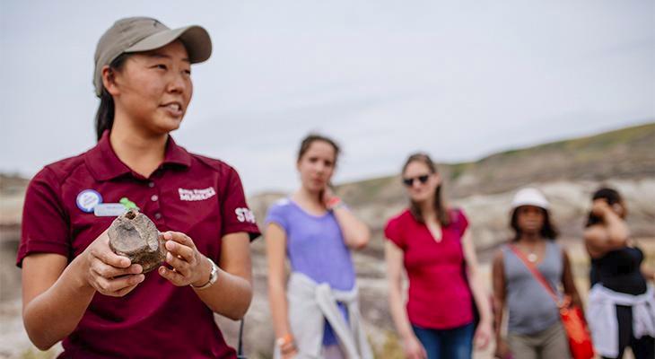 An educator shows a fossil to people in the badlands.