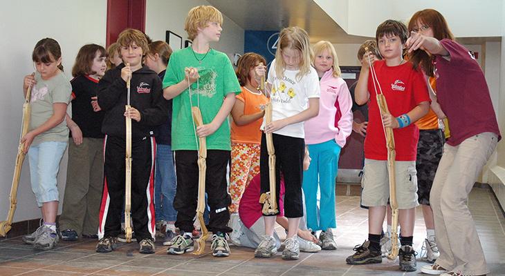 An educator instructs children holding models of raptor legs. 