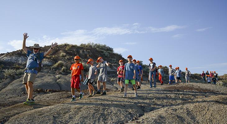 A camp counsellor leads children along a badlands trail.
